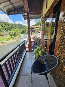 a balcony with tables and chairs and a river at Sumatra Inn & Travel in Bukit Lawang