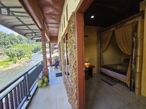 a balcony with a bed and a view of a river at Sumatra Inn & Travel in Bukit Lawang