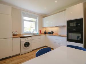 a kitchen with white cabinets and a washer and dryer at Sundale in Strathaven