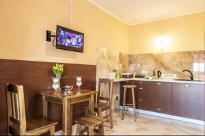 a kitchen with a wooden table and a television on the wall at Pokoje Mirów1A in Mirów +3 photos