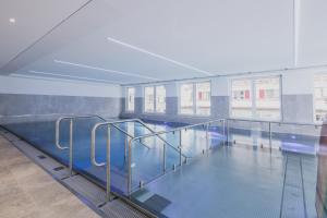 a large swimming pool with blue water in a building at FIRSTpeak Chalets in Zauchensee