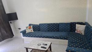 a blue couch in a living room with a table at Appartement kantaoui in Sousse