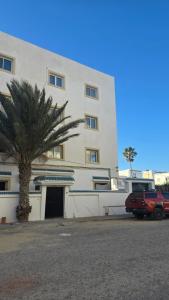 a building with a palm tree in front of it at Appartement kantaoui in Sousse