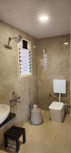 a bathroom with a toilet and a sink and a window at Saavi Resort Shrivardhan in Srīvardhan