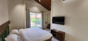 a bedroom with a bed and a flat screen tv at Saavi Resort Shrivardhan in Srīvardhan