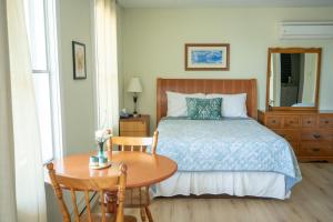 a bedroom with a bed and a wooden table with a table at Bouctouche Bay Inn in Bouctouche