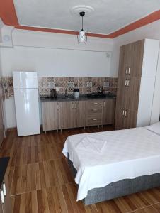 a bedroom with a white bed and a refrigerator at Gökçeada Chrysi Petra pansiyon in Gokceada Town