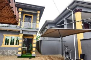 a house with an umbrella in front of it at Lodgeselect in Ibadan
