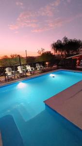 a large blue swimming pool with chairs and a sunset at Cabañas Mi Atardecer in Nono