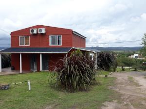 a red house with plants in front of it at Cabañas Mi Atardecer in Nono