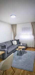 a living room with a blue couch and tables at Apartman Doboj in Doboj