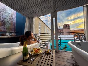 a woman in a bath tub with a bowl of food and a bottle of wine at La Casa del Atrio in Querétaro