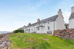 a row of houses on a hill next to the ocean at 2 Bed in Strath oc-s44223 in Gairloch