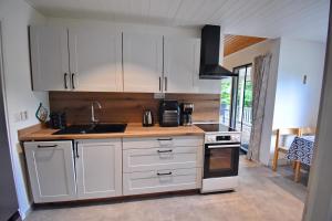 a kitchen with white cabinets and a sink and a stove at "Kiatorp" in Fagerhult +20 photos