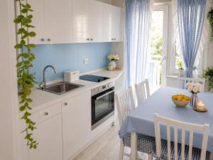 a kitchen with white cabinets and a table with a sink at Nina in Baška Voda