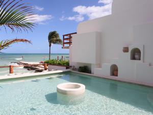a swimming pool in front of a house with the beach at La Palma Beachfront Hotel Boutique in Cancún