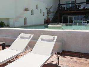 two white chairs sitting next to a swimming pool at La Palma Beachfront Hotel Boutique in Cancún
