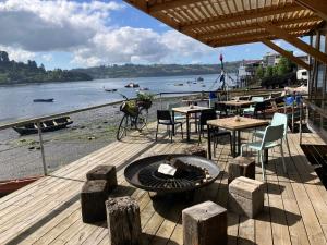 a wooden deck with tables and chairs and a fire pit at Sizigia in Castro