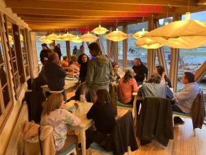 a group of people sitting at tables in a restaurant at Sizigia in Castro +55 photos