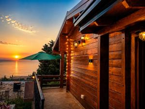 a wooden building with a green umbrella and the ocean at Sea View Luxury Chalet in Šušanj