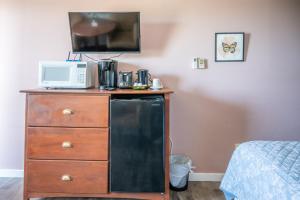 a room with a dresser with a microwave and a refrigerator at Bouctouche Bay Inn in Bouctouche