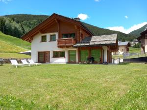 a house with two chairs in a grass field at Chalet Taulei tra Bormio e Livigno in Valdidentro