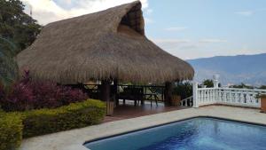 a hut with a swimming pool and a thatch roof at Finca Los Pony Girardota Antioquia in Girardota