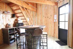 a kitchen with a table and stools in a room at La Cabane Tonneau - Les Pieds dans le Pré in Les Landes-Génusson