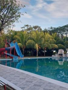 ein Pool mit Rutsche in einem Resort mit Palmen in der Unterkunft L J in Trinidad