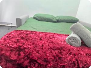 a bed with a red blanket and pillows on it at Double Room with attach Bathroom in London