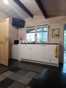 a kitchen with white cabinets in a wooden room at domik in Lapmežciems