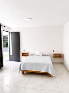 a white bedroom with a bed and a white tile floor at La Palma Coliving in San Lucas Xoloc