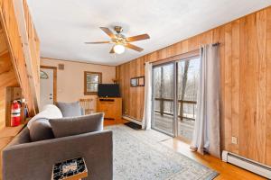 a living room with a couch and a ceiling fan at River Road Treehouse Retreat in Warrensburg