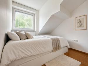 a white bedroom with a bed with a window at Alpine Forest Apartments in Radovljica