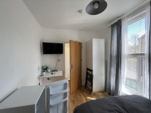 a bedroom with a bed and a desk and a television at Casa Azul in Plumstead
