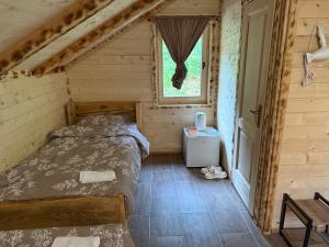 a bedroom in a log cabin with a bed and a window at Bungalow-Guest House Alpina in Vusanje