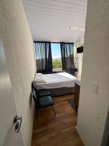 a bedroom with a bed and a chair and a window at Lindo Apto Mobiliado, Smart TV - Caieras in Caieiras