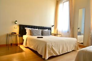 a bedroom with a large white bed with a window at Albergo al Tiepolo in Venice