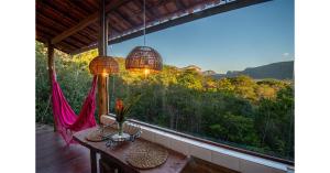 a balcony with a table and a large window at Lilás Hospedagem e Terapias in Vale do Capao