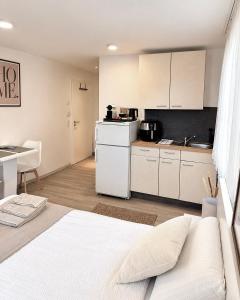 a bedroom with a white bed and a kitchen at STAY - Comfort Apartment in Friedrichshafen