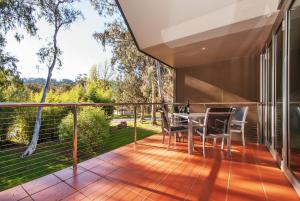 a deck with a table and chairs on a balcony at Centenary Peaks in Bright