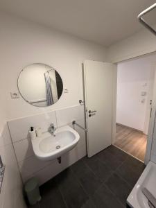 a white bathroom with a sink and a mirror at STAY - Comfort Apartment in Friedrichshafen +29 photos