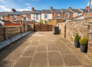 a courtyard with a stone fence and houses at Ushaw HillTop View-Suburban Free Parking Ideal for Work-Stays & Families in Ushaw Moor