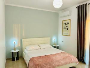 a bedroom with a bed and two candles on tables at Arc Apartment Family - City Center in Divjakë