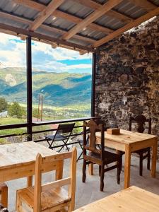 a room with tables and chairs and a view of mountains at Towers Inn Cottage in Mestia