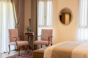 a bedroom with two chairs and a bed and a mirror at Alyasa Village in Jbeil +22 photos