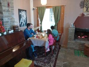 a group of people sitting at a table with a fireplace at Pangeo forest village in Mousthéni