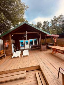 a cabin with a wooden deck with a picnic table at Vikendica Eldar, Ada Bojana in Ulcinj +6 photos