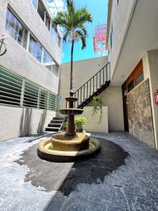 a fountain in front of a building with a palm tree at HOTEL FLAMINGOS DE CIUDAD GUZMAN in Ciudad Guzmán