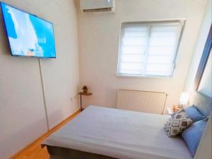 a bedroom with a bed and a flat screen tv at Apartman 053 in Doboj